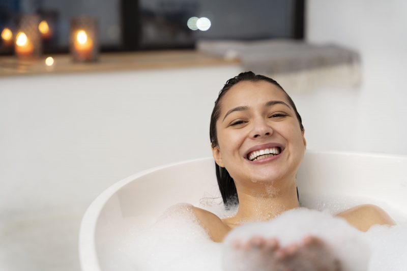 young woman relaxing playing with foam while taking bath